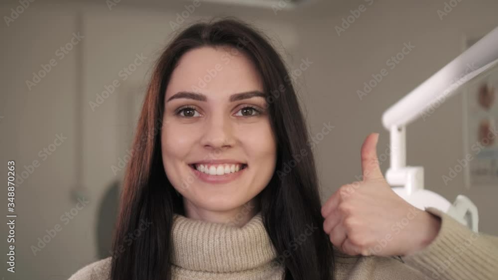 Portrait of a beautiful girl with a charming smile.Snow-white teeth.The girl raises her thumb up. Portrait of a beautiful girl with a charming smile.Snow-white teeth.The girl raises her thumb up.