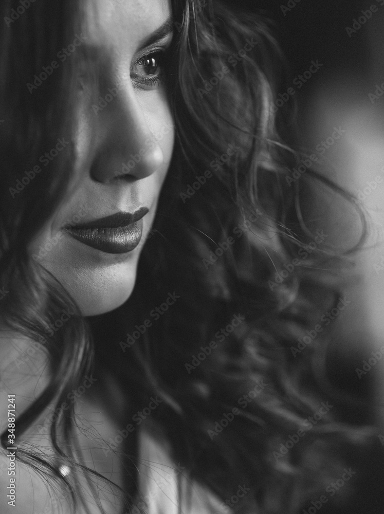 Beautiful young woman with perfect dark curly hair and beautiful make-up with puffy red lips. Close-up. Black and white art photo. Soft selective focus. Beautiful young woman with perfect dark curly hair and beautiful make-up with puffy red lips. Close-up. Black and white art photo. Soft selective focus.
