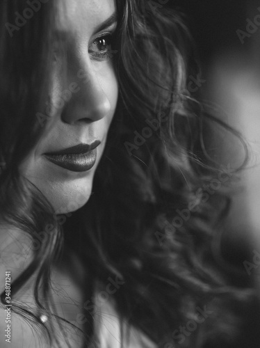 Beautiful young woman with perfect dark curly hair and beautiful make-up with puffy red lips. Close-up. Black and white art photo. Soft selective focus.