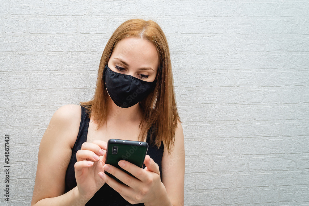 Fototapeta premium beautiful girl in a black medical mask calls the rescue service