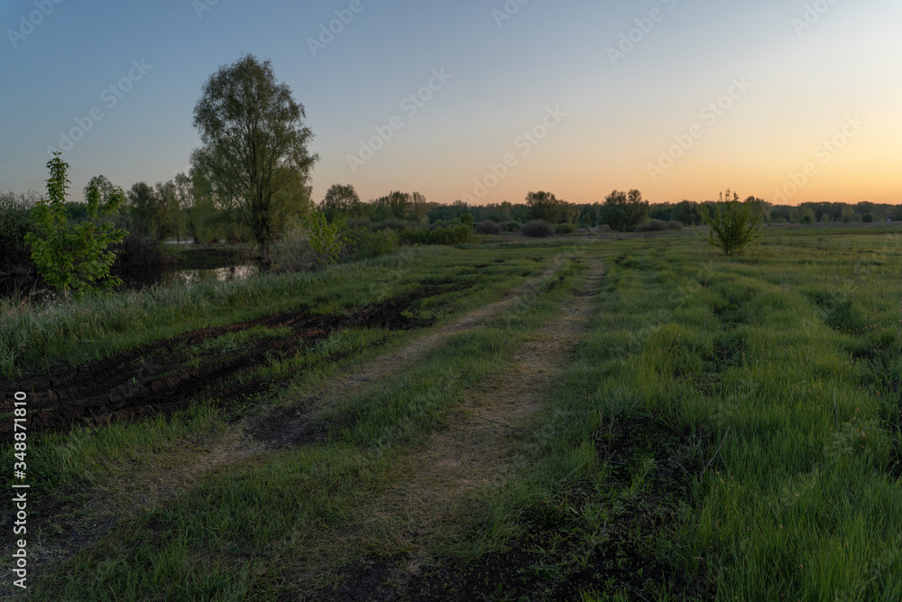 Fototapeta premium Dawn over the lake. Beautiful evening blue sky at sunset with flaming bright light clouds. Warm summer evening at sunset. May.
