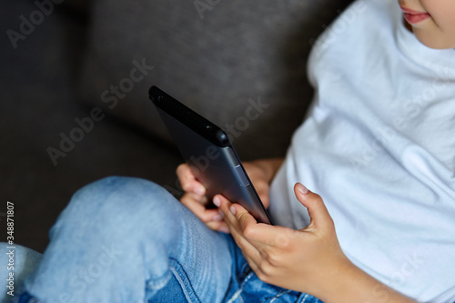 Cute little girl using a digital tablet  sitting on sofa  play game  and smiling
