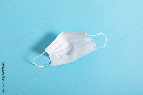 Medical protective mask on light blue background. Minimal medical epidemic concept. Disposable surgical face mask. Flat lay, top view, copy space