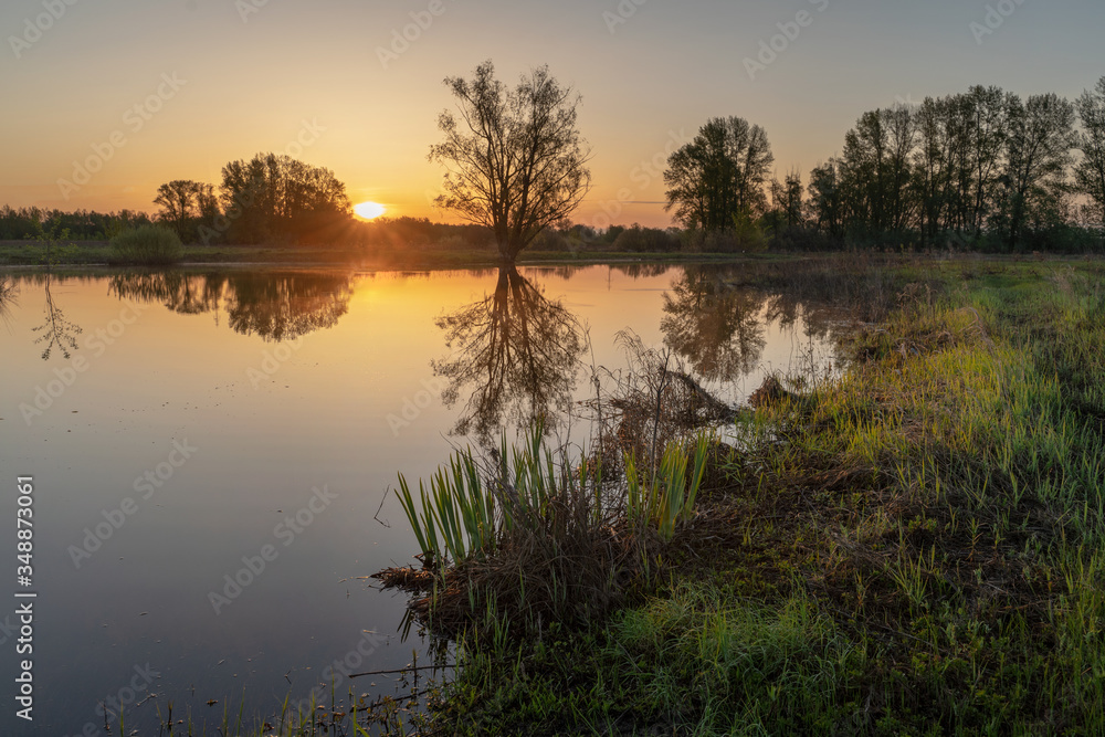 Dawn over the lake. Beautiful evening blue sky at sunset with flaming bright light clouds. Warm summer evening at sunset. May.