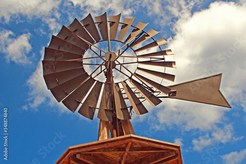 American windmill into the water against a blue sky with white clouds