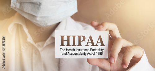 Doctor wearing face mask shows a card with the text HIPPA, The Health Insurance Portability and Accountability Act of 1996,. Medical concept. photo