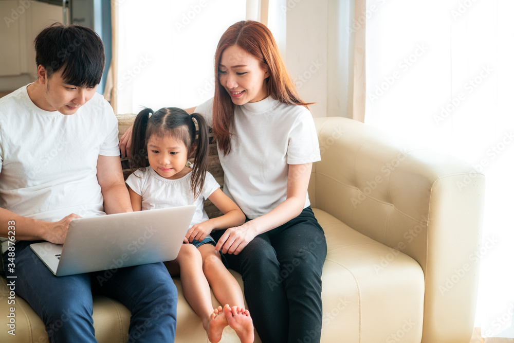 Happy young Asian girl with her lovely parents using laptop computer for education and spent quality time together. Asian family, Social Distancing, homeschooling, work from home or new normal concept Happy young Asian girl with her lovely parents using laptop computer for education and spent quality time together. Asian family, Social Distancing, homeschooling, work from home or new normal concept