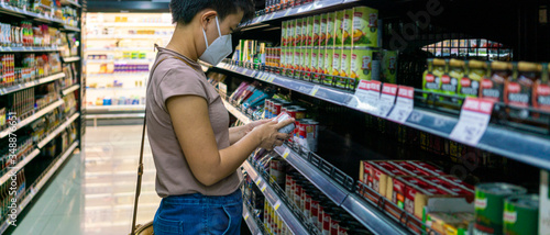 Foto Asian woman wearing face mask selecting foods in supermarket to buy during coronavirus crisis or covid19 outbreak
