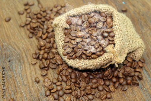 Coffee beans in a sack bag on wood background © studio2013