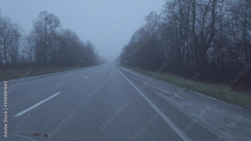 Empty highway near forest and fog at sunset. Autumn foggy landscape with road line, view from car window Empty highway near forest and fog at sunset. Autumn foggy landscape with road line, view from car window