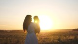 free mom and little daughter are dancing in sunset. Mother and healthy baby in her arms in field. concept of happy childhood. happy child plays with his mother at sunset. happy family concept