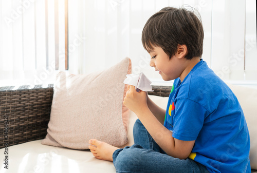 School kid playing with a paper fortune teller,Child boy having fun playing message box toy,Boy enjoy art activity at home, self-isolation, online education, home schooling, distance learning concept photo
