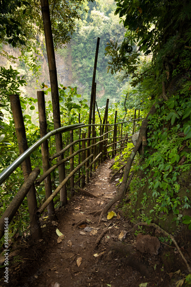 Trail with bamboo fences and boards, heading towards the waterfall at Tumpak Sewu waterfall, in East Java, Indonesia. Trail with bamboo fences and boards, heading towards the waterfall at Tumpak Sewu waterfall, in East Java, Indonesia.