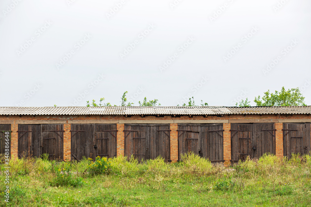 Old cowshed. Large wooden gate and dried wood. Old brick building Old cowshed. Large wooden gate and dried wood. Old brick building