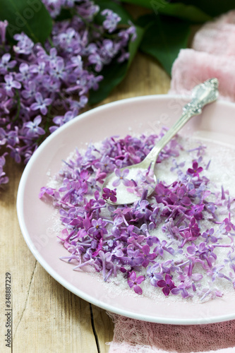 Lilac flowers with sugar  lilac and pink napkin on a wooden background. Rustic style.