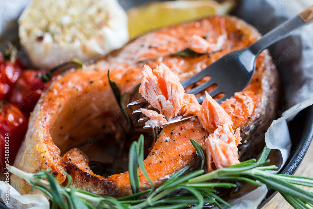 baked salmon steak with rosemary, lemon and spices in a black pan on a blue rustic background. Balanced diet baked salmon steak with rosemary, lemon and spices in a black pan on a blue rustic background. Balanced diet