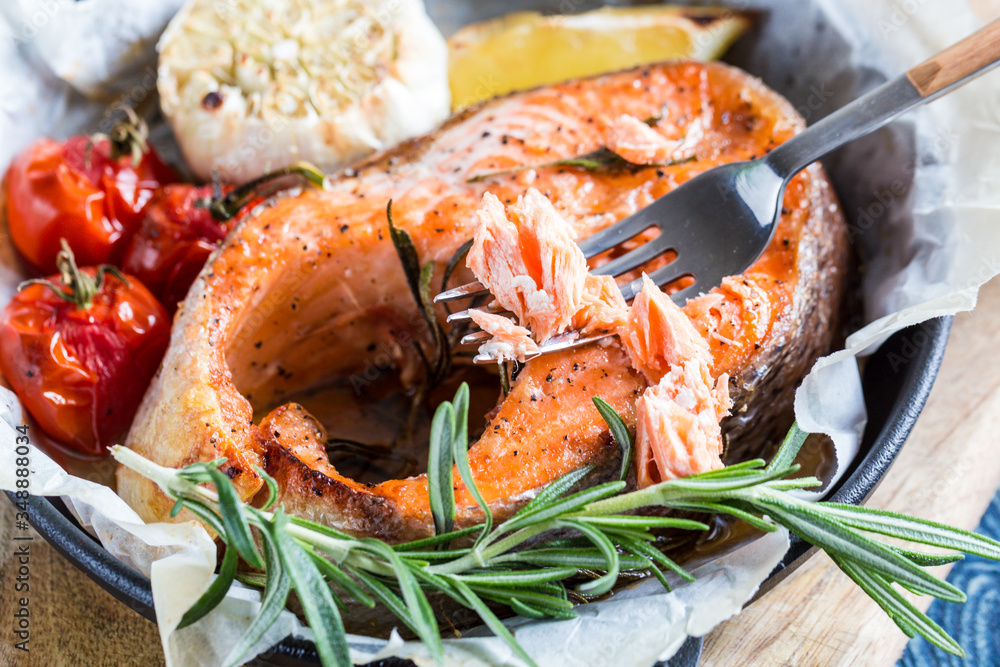baked salmon steak with rosemary, lemon and spices in a black pan on a blue rustic background. Balanced diet baked salmon steak with rosemary, lemon and spices in a black pan on a blue rustic background. Balanced diet
