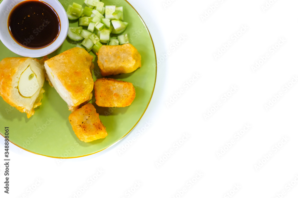 mpek-mpek or pempek. fish and tapioca served on a green plate with rich sweet and sour sauce called kuah cuka or vinegar sauce. Isolated on white background mpek-mpek or pempek. fish and tapioca served on a green plate with rich sweet and sour sauce called kuah cuka or vinegar sauce. Isolated on white background