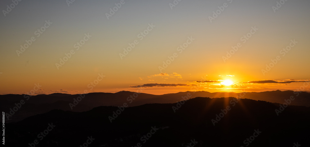Beautiful sunset with sun rays with hills silhouette