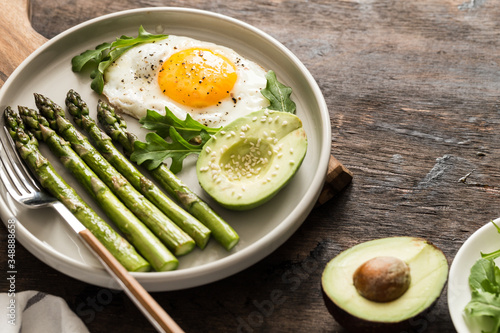 Healthy homemade breakfast with asparagus, fried egg, avocado and arugula. quarantine healthy eating concept. keto diet