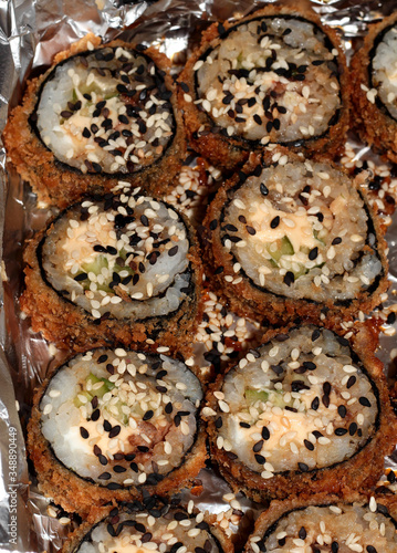 Fried sushi with sesame seeds. Sushi with cucumber, cheese, tuna and honey sauce.