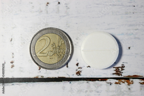 expensive drugs 2 euro coin on a wooden table with big round white pill