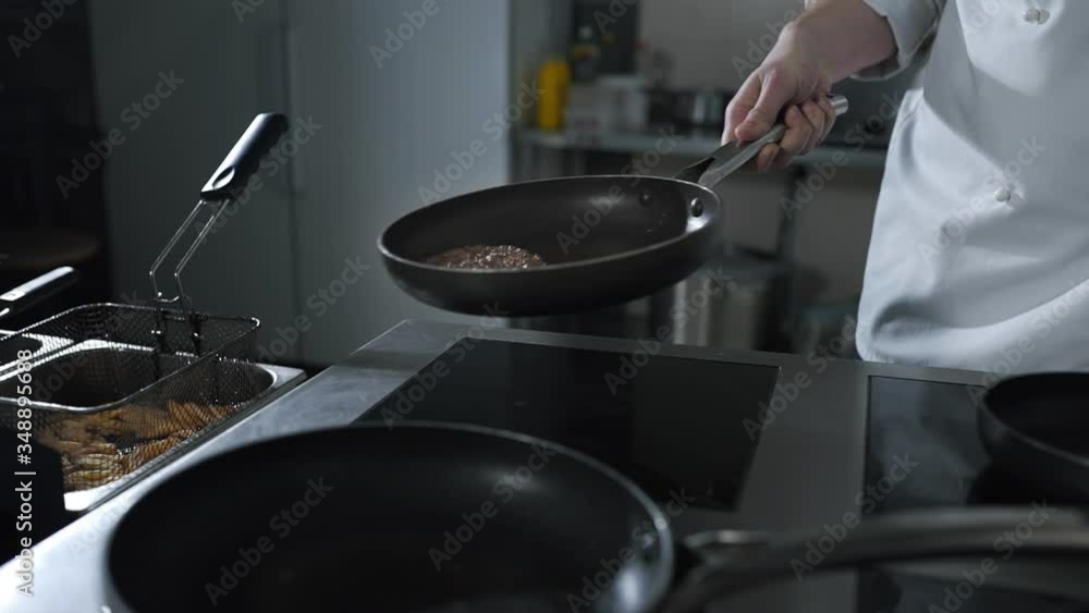 chef tosses roasting beef on the hot pan at the restaurant kitchen chef tosses roasting beef on the hot pan at the restaurant kitchen