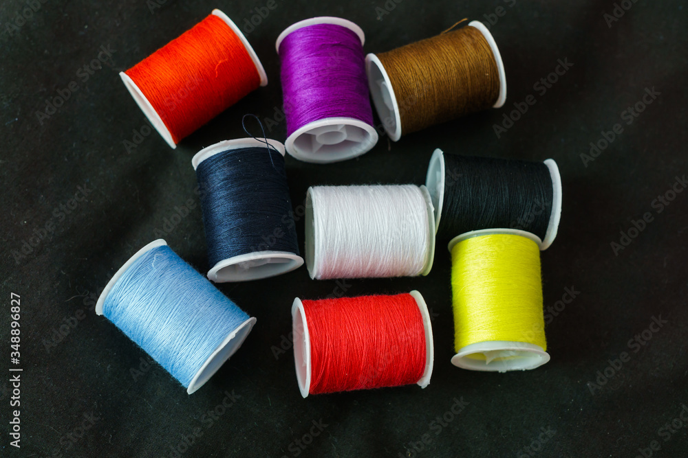 Multi-colored spools of thread close-up on a dark background. Multi-colored spools of thread close-up on a dark background.