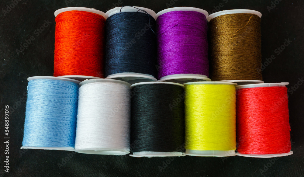 Multi-colored spools of thread close-up on a dark background. Multi-colored spools of thread close-up on a dark background.