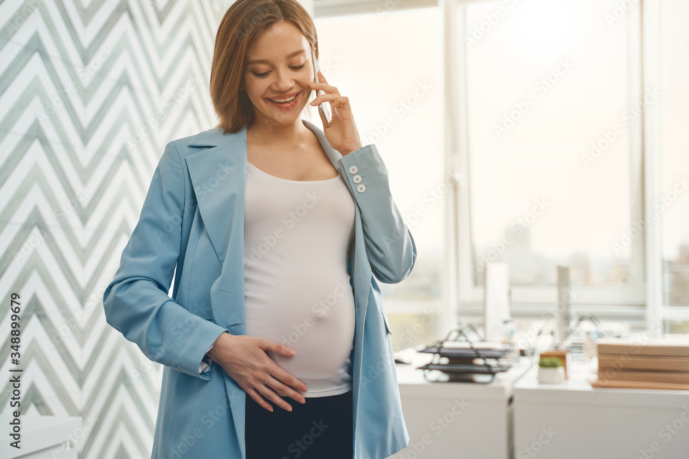 Charming pregnant woman talking on cellphone at work Charming pregnant woman talking on cellphone at work