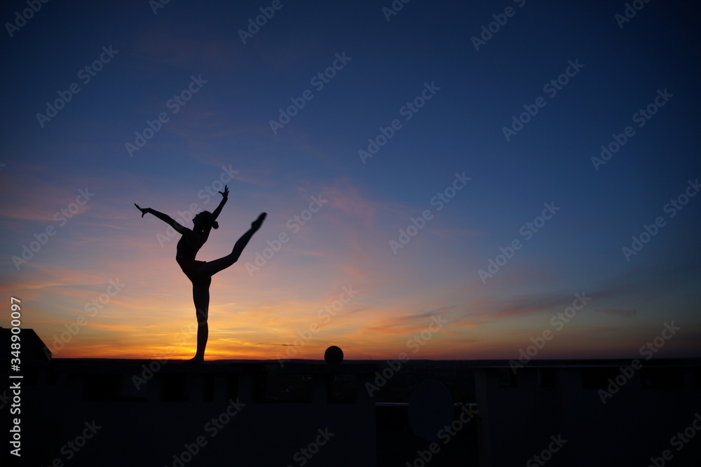 dancer in the dance does the splits in the air against the sunset