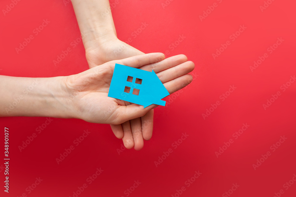 hands hold the house. the family's hands hold a blue cardboard house against a bright background. home, insurance, and family care. hands hold the house. the family's hands hold a blue cardboard house against a bright background. home, insurance, and family care.