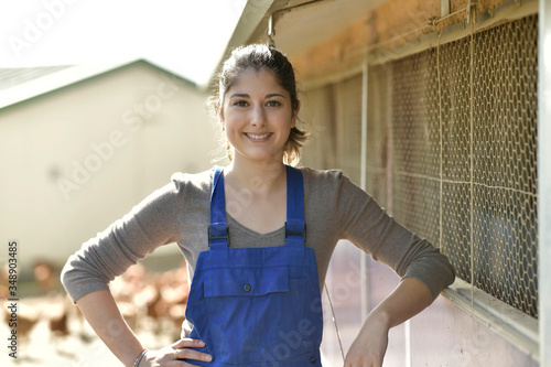 Smiling young farmer standing in poultry yard photo