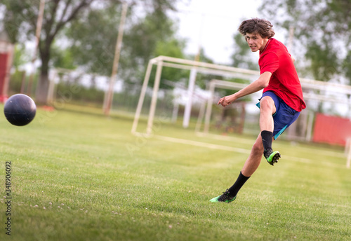 Soccer player kicks ball in a field