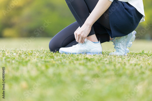 靴紐を結び運動の準備をする若い女性