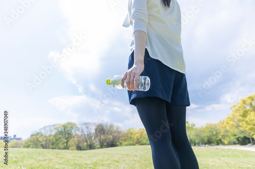 ペットボトルを持ち佇む運動着姿の若い女性