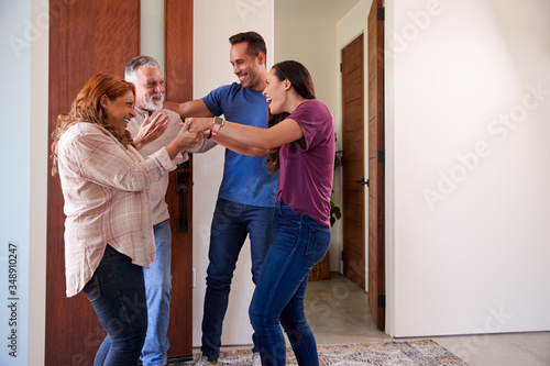Tableau sur toile Couple Greeting Senior Parents At Front Door As They Come To Visit