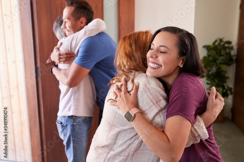 Photos Couple Greeting Senior Parents At Front Door As They Come To Visit