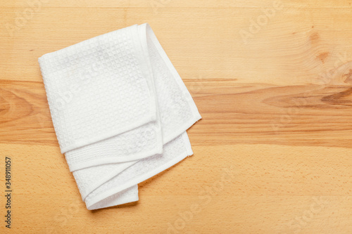 Top view on a wooden table with a linen kitchen towel or textile napkin.