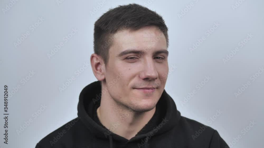 Attractive guy smiles sincerely, looking at the camera, isolated on white blurred background. Close up. 4k Attractive guy smiles sincerely, looking at the camera, isolated on white blurred background. Close up. 4k