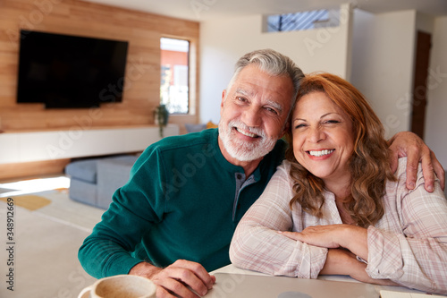 Portrait Of Senior Hispanic Couple At Home Sitting At Table Using Laptop Together
