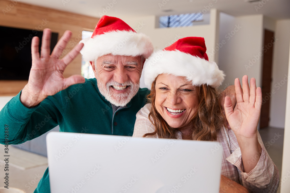 Senior Hispanic Couple Wearing Santa Hats With Laptop Having Video Chat With Family At Christmas Senior Hispanic Couple Wearing Santa Hats With Laptop Having Video Chat With Family At Christmas