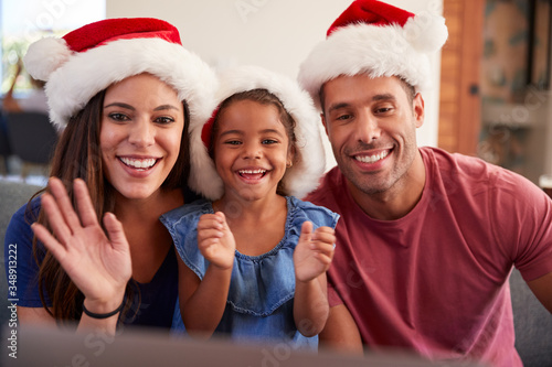 Hispanic Family Wearing Santa Hats With Laptop Having Video Chat At Christmas