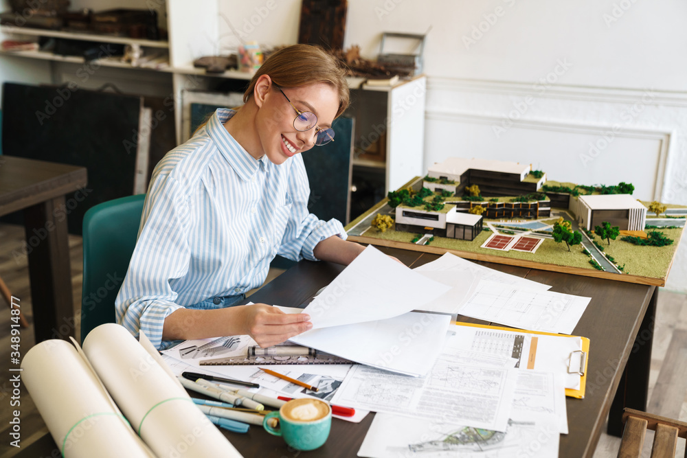 Photo of woman architect working with drawings while designing draft