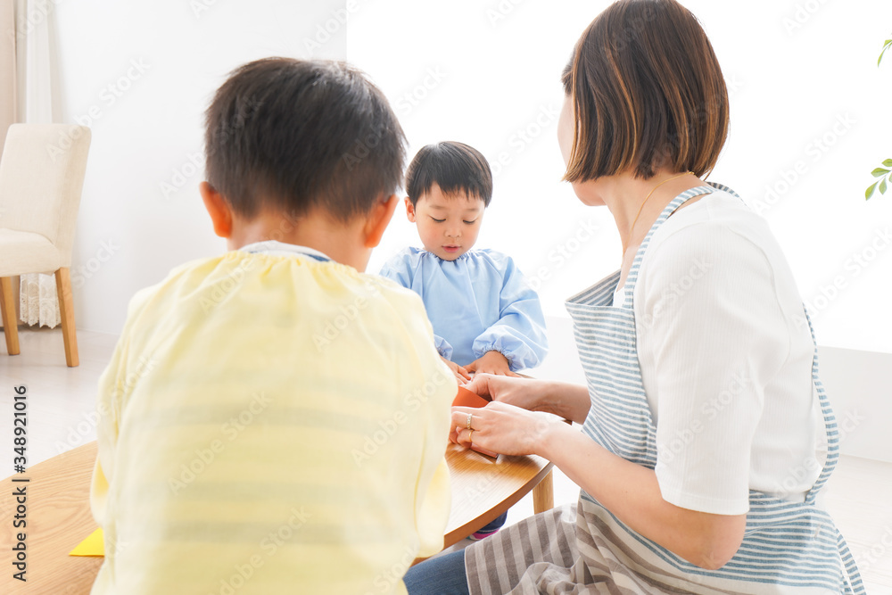 Obraz premium 幼稚園で折り紙をする子どもと先生