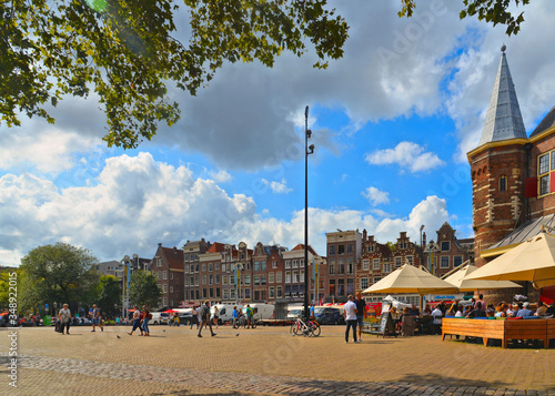 Amsterdam, Holland Cityscape with De Waag medieval building on Nieuwmarkt square or New Market square with people and blue cloudy sky, photo