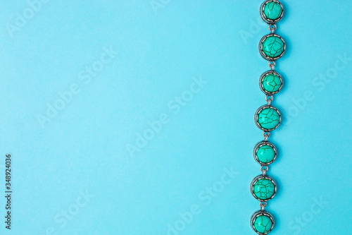 Turquoise bracelet on a blue background with copyspace. Top view.