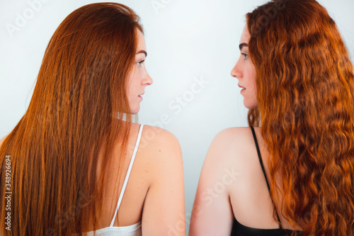 portrait of two redheaded young women both standing back half a turn on isolated white backgroung, beauty and style concept