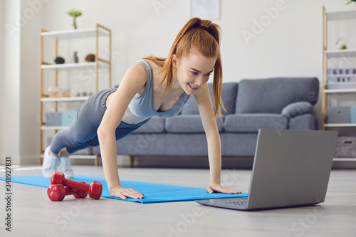 Online sport exercises at home. Workout at home. Redhead girl doing exercises at home.