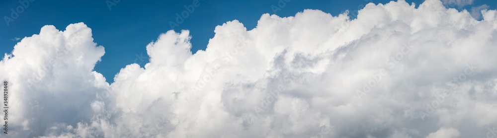 Fototapeta premium Wide background with copy space with white puffy clouds on a blue sky